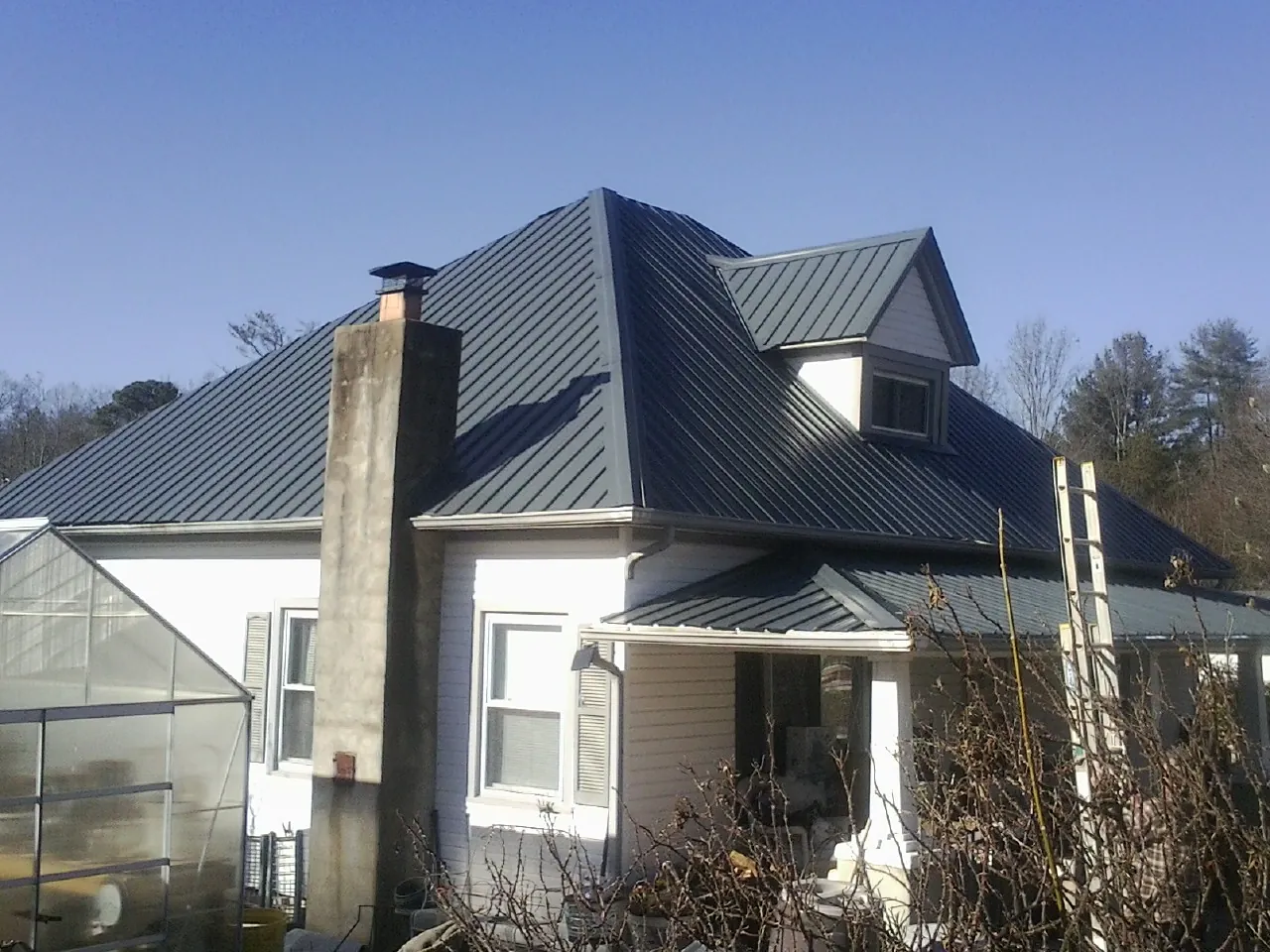 Dark blue standing seam metal roof on a white farmhouse with dormer — Slate & Tile Roof Repair by Roofing Brothers in Byesville
