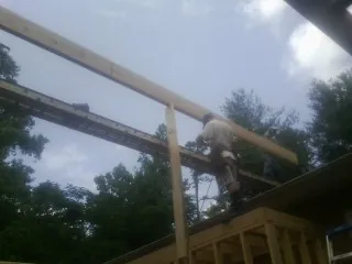 Carpenter setting a ridge beam over a new addition frame — Ice Dam Removal by Roofing Brothers in Byesville