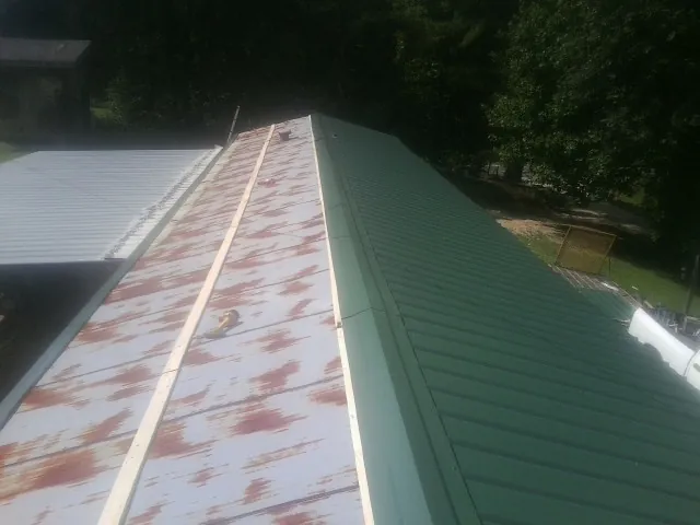 Old rusted panels beside newly installed green metal roofing — Wind Damage Roof Repair by Roofing Brothers in Byesville