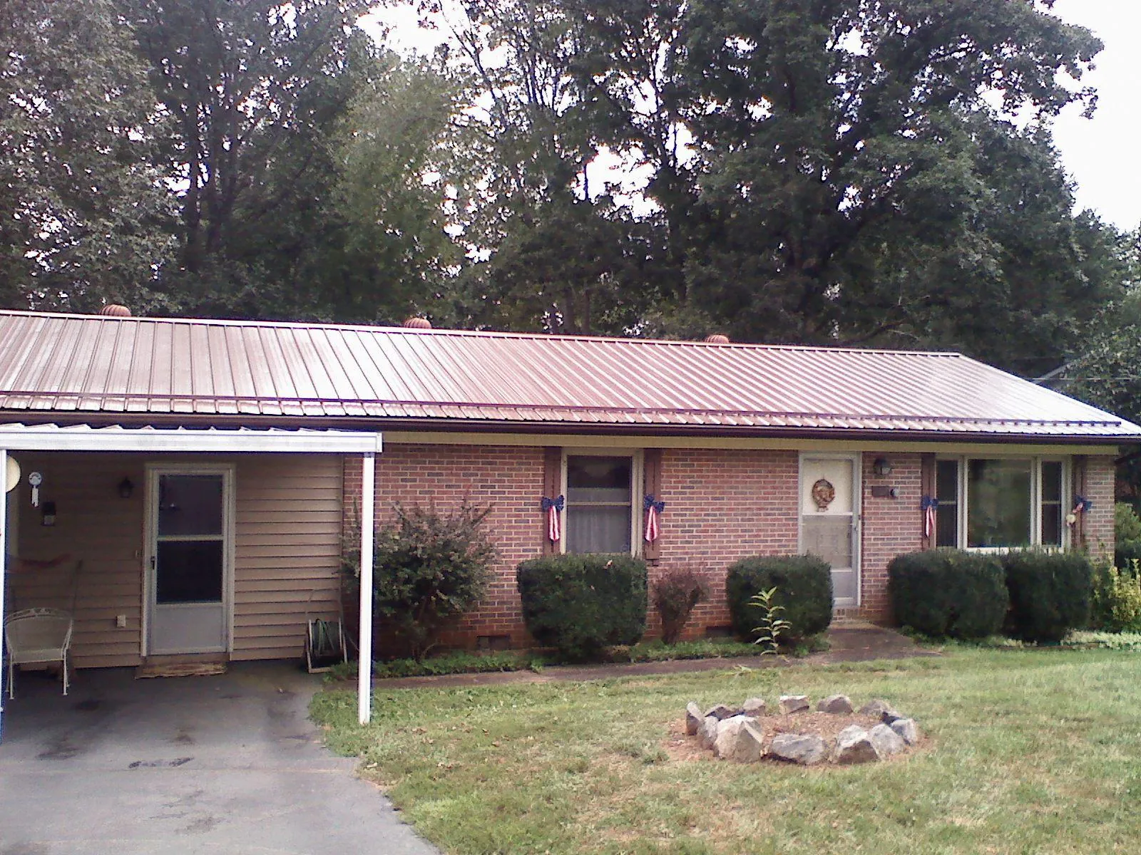 Bronze metal roof and carport on a brick ranch home — Roof Repair work by our crew in Byesville