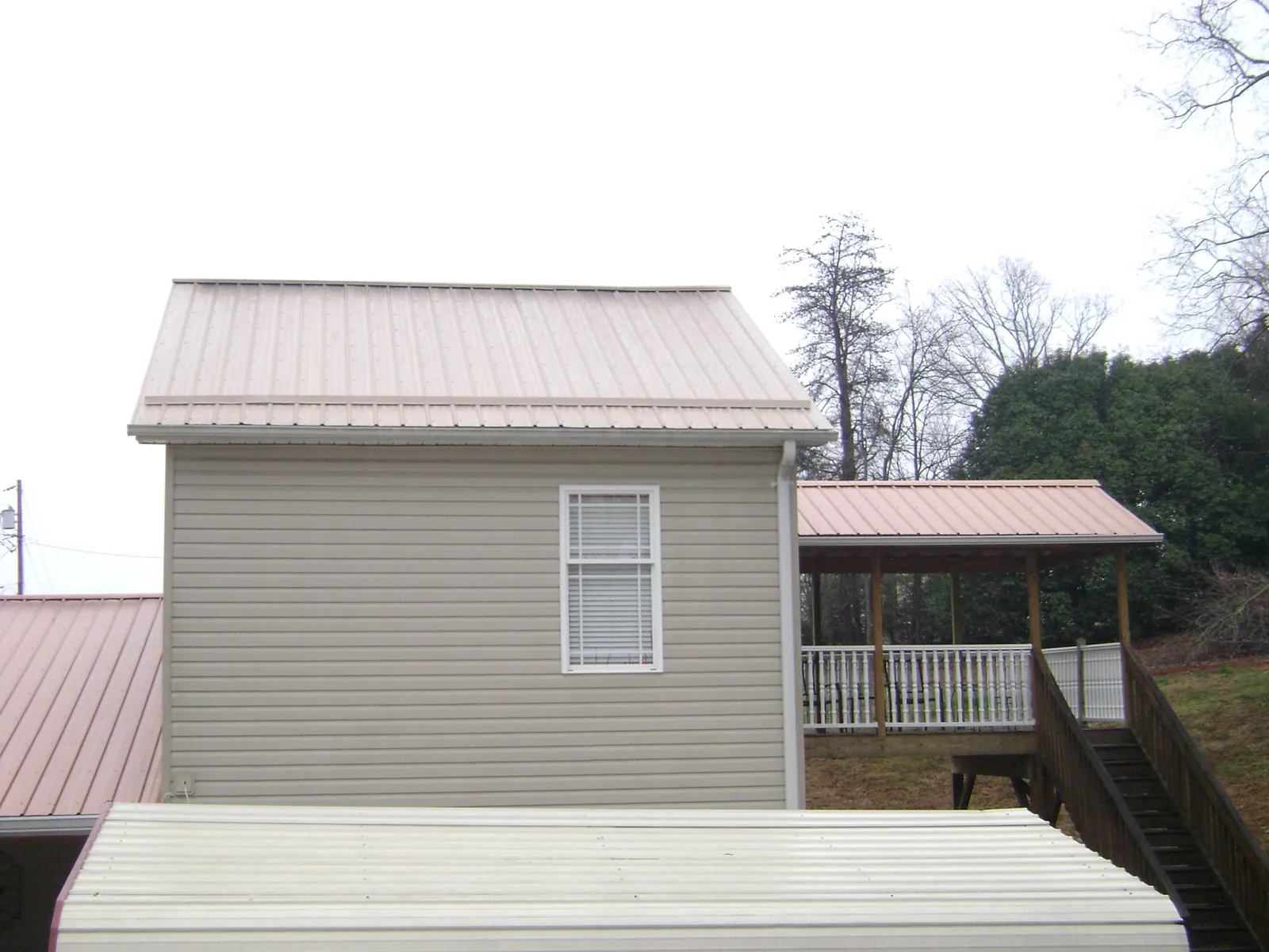 Tan metal roofs on a two story addition and attached porch, from a Roof Replacement job in Byesville