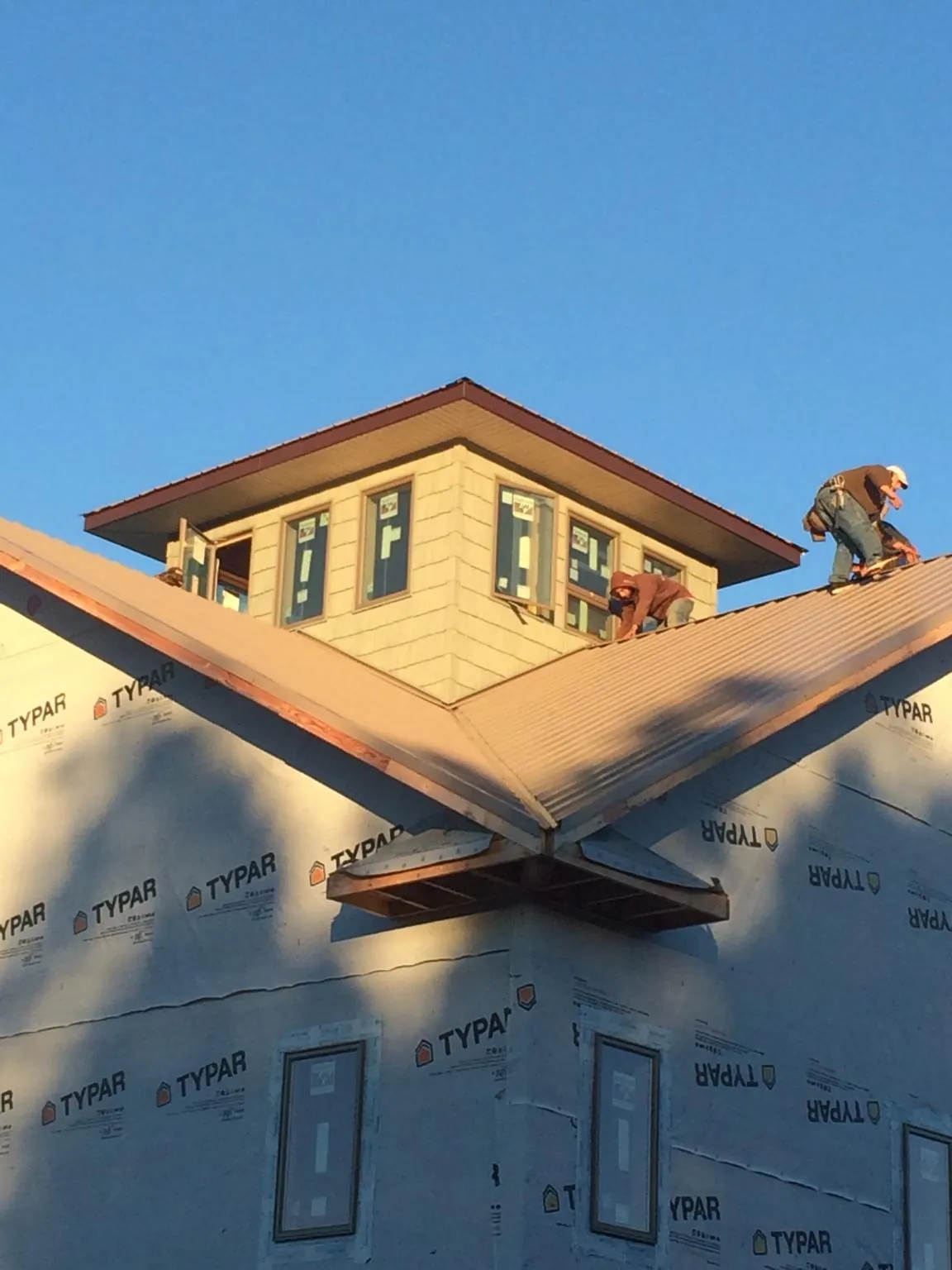 Roofers working around a rooftop cupola on a new metal roof at sunset — Roof Waterproofing in Byesville by Roofing Brothers